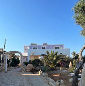 um grande edifício branco com palmeiras em frente em B H Lampedusa em Lampedusa