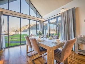 a dining room with a table and chairs and large windows at Cranesbill in Bamburgh