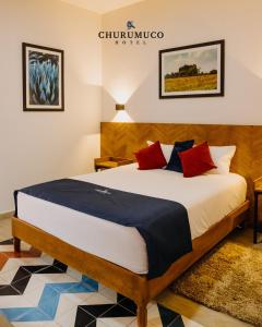 a bedroom with a large bed with red and blue pillows at HOTEL CHURUMUCO in San José Iturbide