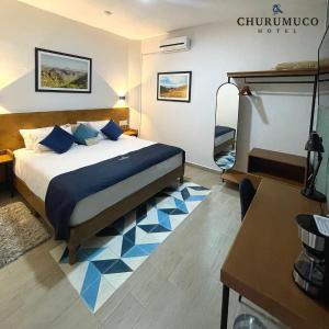 a bedroom with a bed with blue pillows and a desk at HOTEL CHURUMUCO in San José Iturbide