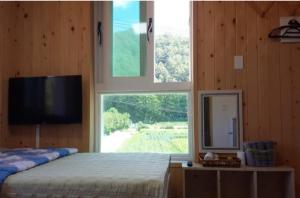 a bedroom with a bed with a television and a window at Odaesan Moonlight in Pyeongchang