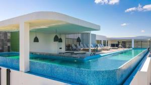 a swimming pool with blue tiles on the side of a building at Apartamento Aldea Zama 7 in Tulum