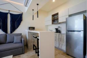 a kitchen with a stainless steel refrigerator and a couch at Apartamento Aldea Zama 7 in Tulum