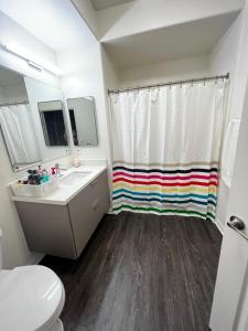 baño con cortina de ducha de arco iris y aseo en Wanda’s pad, en Los Ángeles