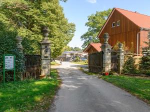 uma entrada com um portão e um celeiro vermelho em Cozy holiday home on a horse farm in the Lüneburg Heath em Eschede