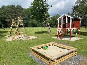 um parque infantil com um conjunto de jogos e uma casa em Cozy holiday home on a horse farm in the Lüneburg Heath em Eschede