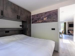 een slaapkamer met een bed en een schilderij aan de muur bij Group accommodation with infrared sauna, in a holiday park in nature in Hoenderloo