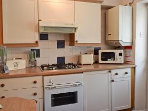 a kitchen with white cabinets and a stove and microwave at Clarksville in Leyburn