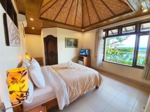 a bedroom with a bed and a large window at Hotel Genggong in Candidasa