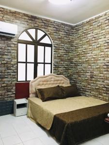 una camera con un grande letto e un muro di mattoni di Seri Lagenda Apartment a Kuah