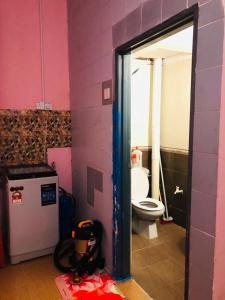 een badkamer met een toilet in een roze muur bij Seri Lagenda Apartment in Kuah