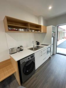 a kitchen with a sink and a washing machine at Sierra Motel and Apartments in Omarama