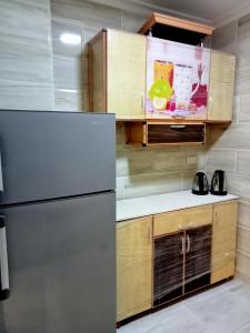 een keuken met een koelkast en houten kasten bij Relax Guest House in Zes oktober (stad)