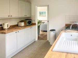 a kitchen with white cabinets and a sink at Courtfield Bungalow in Totnes