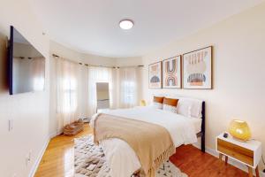 a white bedroom with a large bed and a tv at Five75 Lux BOS - Boho Chic in Boston