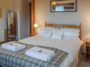 a bedroom with a large bed with towels on it at Brandystone Cottage in Oban