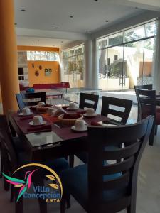 a dining room with a table and chairs and windows at Villa Concepción Lodge in Anta