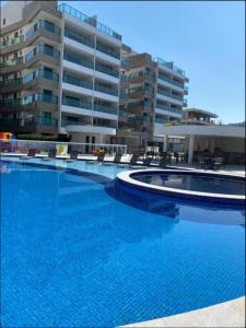 una gran piscina frente a un gran edificio en Praia dos Anjos Residence Clube, en Arraial do Cabo