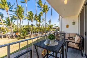 a table and chairs on a balcony with palm trees at RARE Upscale Oasis - 2 Bed,2 Bath - Kuau Plaza - Paia in Paia
