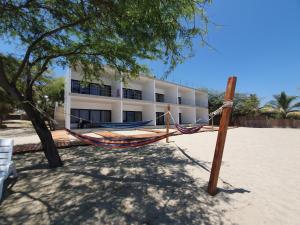 a hammock on the beach in front of a building at Las Hamacas in Canoas De Punta Sal