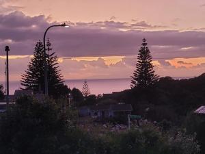 a sunset with a street light and trees and the ocean at Three Cheers in Leigh