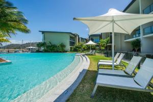 a pool with two lounge chairs and an umbrella at Blue on Blue Studio Room 1352 in Nelly Bay