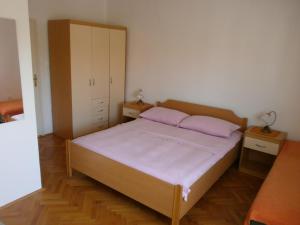 a bedroom with a bed with two purple pillows at Apartments Juraga in Murter