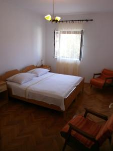 a bedroom with a large white bed and a window at Apartments Juraga in Murter