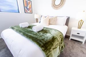 a bedroom with a white bed with a green blanket on it at Sunny townhouse Central city 2 bedroom in Christchurch