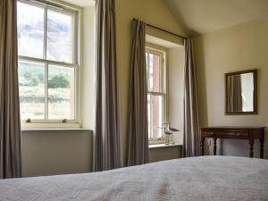 a bedroom with a bed and two windows at Sharrow Cottage in Watermillock