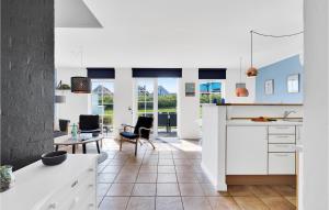 uma cozinha com armários brancos e uma mesa e cadeiras em Cozy Home In Brenderup Fyn With Wifi em Bro