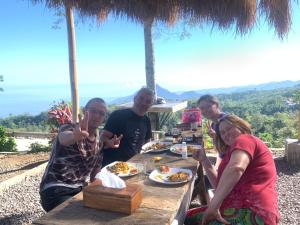 un grupo de personas sentadas en una mesa comiendo comida en Wanagiri Campsite, en Gitgit