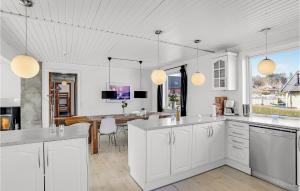 a kitchen with white cabinets and a dining room at Awesome Home In Allinge With 5 Bedrooms And Wifi in Allinge
