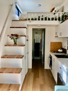 una cucina con armadietti bianchi e scale in una casetta minuscola di Tiny Nerak a Nethercote