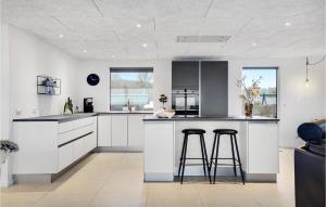 une cuisine avec des placards blancs et deux tabourets de bar dans l'établissement 3 Bedroom Stunning Home In Ebeltoft, à Ebeltoft