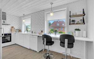 Una cocina blanca con dos sillas negras. en 4 Bedroom Lovely Home In Frederikshavn, en Frederikshavn