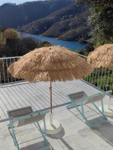two chairs and a straw umbrella and a table and bench at Vale Da Misarela in Geres