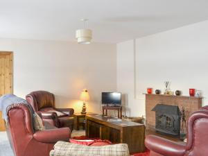 een woonkamer met lederen stoelen en een open haard bij Rose Cottage - Beaufort Estate in Belladrum