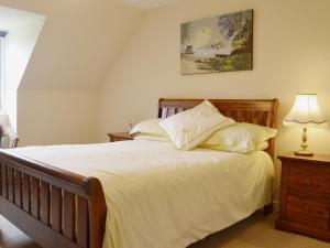 een slaapkamer met een groot bed met witte lakens en kussens bij Rose Cottage - Beaufort Estate in Belladrum