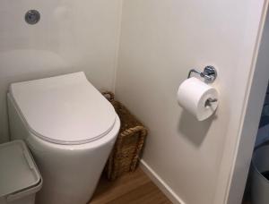 a white toilet in a bathroom with a roll of toilet paper at Tiny Nerak in Nethercote