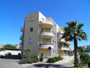 a tall white building with a palm tree in front of it at Appartement 2 pièces avec climatisation, parking, proche plage, commerces et activités - Classé 3 étoiles - FR-1-338-426 in Sète +12 photos