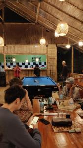 a group of people sitting at a table with a pool table at Rimba eco Resort in Tomohon
