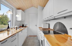 a kitchen with white cabinets and a wooden ceiling at Cozy Home In Gedser With Wifi in Gedser