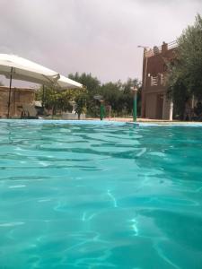 a swimming pool with blue water and an umbrella at Walid in Marrakech