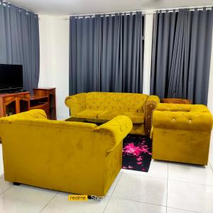 um sofá amarelo e duas cadeiras numa sala de estar em Juliana Homestay em Jitra