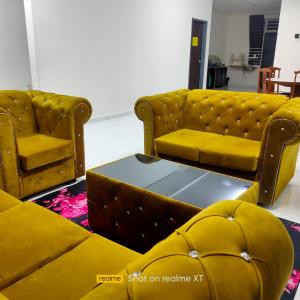 Sala de estar con 2 sillas amarillas y mesa en Juliana Homestay en Jitra