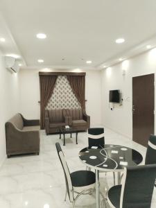 uma sala de estar com uma mesa e cadeiras e um sofá em هوتيل نجران للشقق الفندقية em Najran
