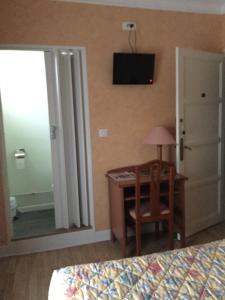 a bedroom with a desk and a television on the wall at Aux Quatre Vents in Saulieu