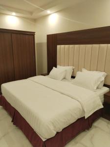 a bedroom with a large white bed with a wooden headboard at هوتيل نجران للشقق الفندقية in Najran