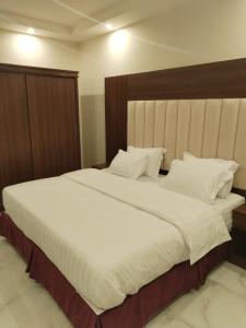 a bedroom with a large white bed with a wooden headboard at ابراج التاج للشقق الفندقية in Najran